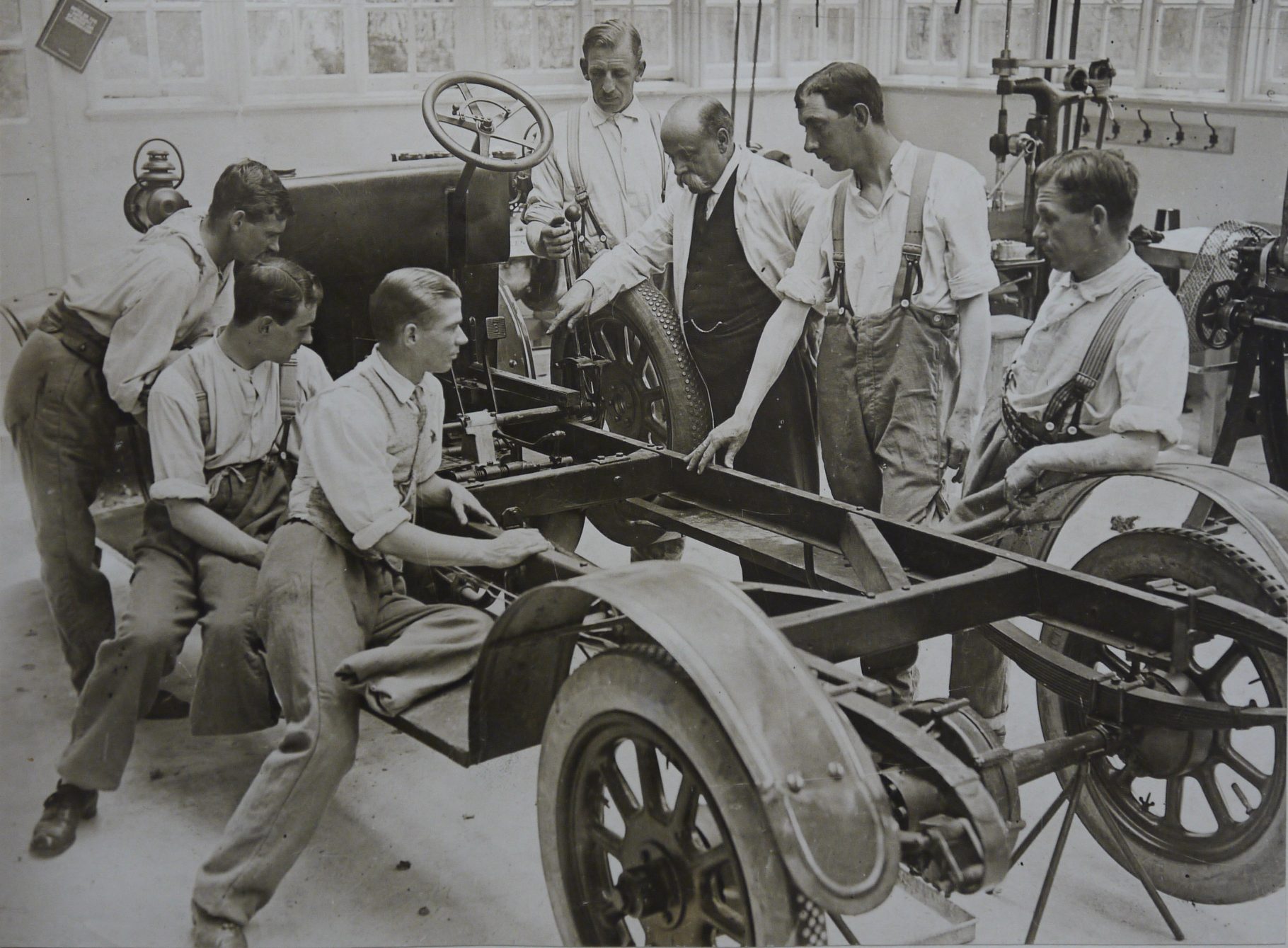 Group of men with leg amputations looking at the chassis of a car
