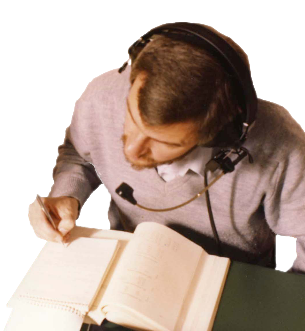 Photo of man with headphones making notes