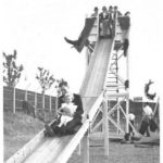 Photo of a man and a child using the slide at a garden party