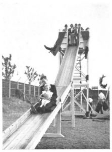 Photo of a man and a child using the slide at a garden party