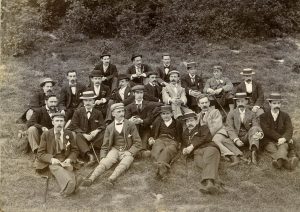 Photo of male ramblers sitting in countryside wearing suits and boaters, 1897