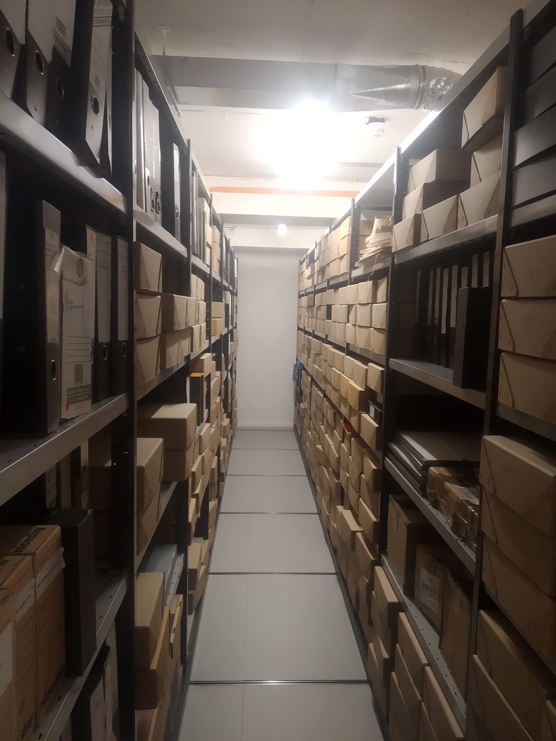 An image of one of the strongrooms at the University of Westminster archive, showing a corridor of shelving full of archival storage boxes.