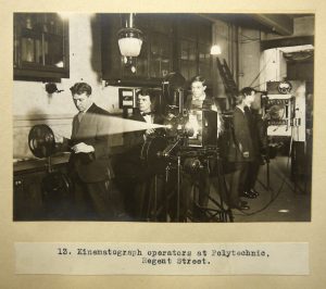 Black and white photograph of men working a film projector