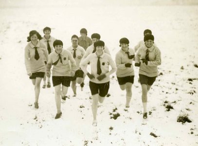 Photograph showing women in athletics kit running in the snow.